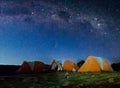 Orange tents illuminated before Mount Kilimanjaro and bright Milky Way