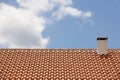 Orange tile roof with chimney over a blue sky