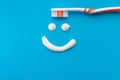 Orange toothbrush on a blue background with a smile painted with toothpaste. The view from the top Royalty Free Stock Photo