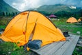 Orange tourist tent on a hill above the ravine. tent stands in the thick green grass at sunset. Summer landscape Royalty Free Stock Photo