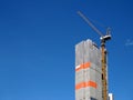 gray construction canvas sheet covered apartment building structure for safety with tower crane working on rooftop Royalty Free Stock Photo