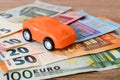 Orange toy car on different euro banknotes. Concept of car buying, renting, service, repair and insurance costs. Planning for Royalty Free Stock Photo