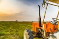 Orange tractor and harvested land Royalty Free Stock Photo