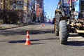 Orange traffic cones enclose a repair area along the edge of a city street