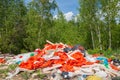 Orange trash in the forest against a green forest and blue sky. Environmental pollution. The concept of man and nature.