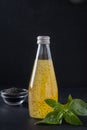 Orange tropical juice with basil seeds in bottle on black. Close up