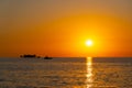 tropical sunset with little island and fisherman boat on horizon line Royalty Free Stock Photo