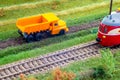 Orange truck on model train layout pass by passenger train