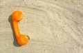 Orange tube of an old vintage phone is lying on the sand