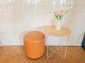 Orange tulips in a modern white vase on a cream colored table beside a round chair. The decoration of the chairs and tables in the Royalty Free Stock Photo