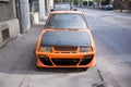 Orange tuned car abandoned on the sidewalk