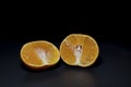 Orange in two cut pieces on black background Royalty Free Stock Photo