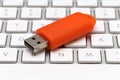 Orange USB pen drive arranged on white keyboard Royalty Free Stock Photo