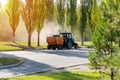 Orange vacuum sweeper towed by a blue tractor removes dust from the roads : September 20, 2021 Agidel, Russia
