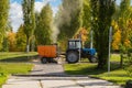September 20, 2021 Agidel, Russia: Orange vacuum sweeper, towed by a blue tractor, works on cleaning city streets