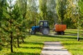 Orange vacuum sweeper, towed by a blue tractor, works on street cleaning : September 20, 2021 Agidel, Russia