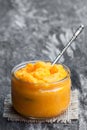 Orange vagetables puree in glass jar on wooden table