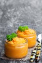Orange vagetables puree in glass jars on wooden table