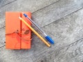 Orange vintage notebook with pen and pencil on wooden table. Creative writing concept. Flat lay top view. Vintage style