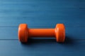 Orange vinyl dumbbell on blue wooden table