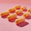 Orange vitamin pills arranged on a soft pink background in a well-lit studio Royalty Free Stock Photo