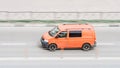Orange volkswagen van vehicle on city road. Fast moving car on street. Delivery van fast delivers in a city. Compliance with speed