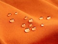 Orange waterproof fabric with water drops close up