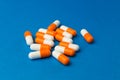 Orange white capsules pills on a blue background. Medical background, template. Royalty Free Stock Photo