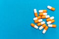 Orange white capsules pills on a blue background. Medical background, template. Royalty Free Stock Photo