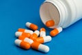 Orange white capsules & x28;pills& x29; were poured from a white bottle on Royalty Free Stock Photo