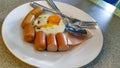 The food has hot dogs and fried eggs on a beautiful dish.