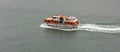 Orange-and-white life boat moving fast in the water