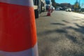 Orange, white traffic cone stands on road separating traffic flows close up, some lanes are completely filled with cars