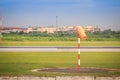 Orange windsock or wind vane in moderate wind on red white pole against clear blue sky on sunny day at aviation area. Wind vane di Royalty Free Stock Photo