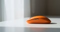 Orange Wireless Computer Mouse on White Desk in Natural Light Royalty Free Stock Photo