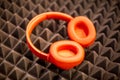 Orange wireless overhead monitor headphones lie on a dark foam rubber noise canceling panel. close-up soft focus, blur