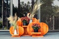 Orange wooden handmade craft halloween style flower-stand with chrysanthemum and dried herb flowers at house porch. Autumn
