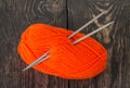 Orange wool skein of yarn and knitting needles on dark boards Royalty Free Stock Photo
