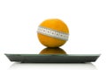 Orange wrapped with measuring tape on a scale Royalty Free Stock Photo