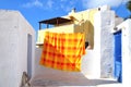 Pyrgos, Santorini / Greece: An orange and yellow bedspread, hanging to dry on a rooftop in the village of Pyrgos