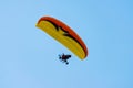 Orange, Yellow, and Black Paramotor Soaring in Blue Sky Royalty Free Stock Photo