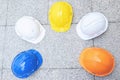 Orange, yellow, blue, white hard safety wear helmet hat in the project at construction site building on concrete floor