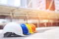 Orange, yellow, blue and white hard safety wear helmet hat in the project at construction site building on concrete floor on city.