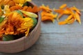 Orange and yellow calendula officinalis flowers in a wooden bowl on the board background. Close-up, copy space. Royalty Free Stock Photo