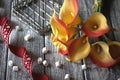 Orange yellow calla lilies with red ribbon and white marshmallows on wooden gray background. Royalty Free Stock Photo