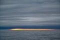 Bright orange yellow colors of sunset in small strip on horizont over dark sea with dark cloudy sky, Antarctic Ocean, Antarctica Royalty Free Stock Photo