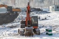 Orange and yellow excavators at a construction site in winter