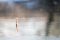 Orange-yellow fishing float in the river water. Spring fishing, bright colors of water and nature. Solar reflection in the water. Royalty Free Stock Photo