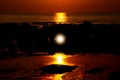 Orange yellow golden vibrant sunset on tropical island over low tide ocean with reflection of sun beam in water and sunburst Royalty Free Stock Photo