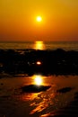 Orange yellow golden vibrant sunset on tropical island over low tide ocean with reflection of sun beam in water and sunburst Royalty Free Stock Photo